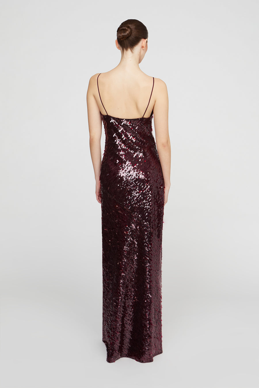 Woman wearing a long, dark sequined dress on a white background