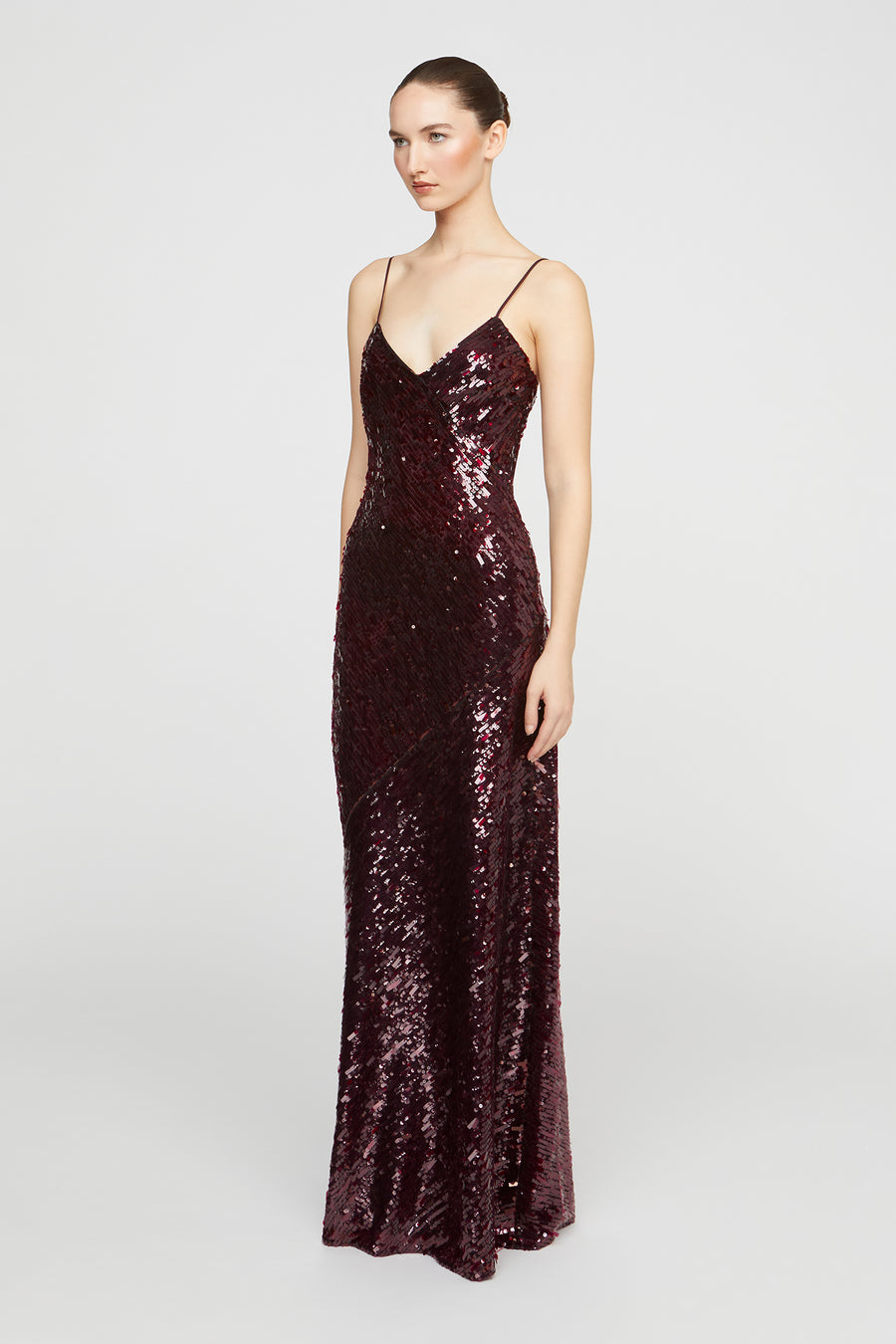 Woman wearing a burgundy sequin evening gown on a white background