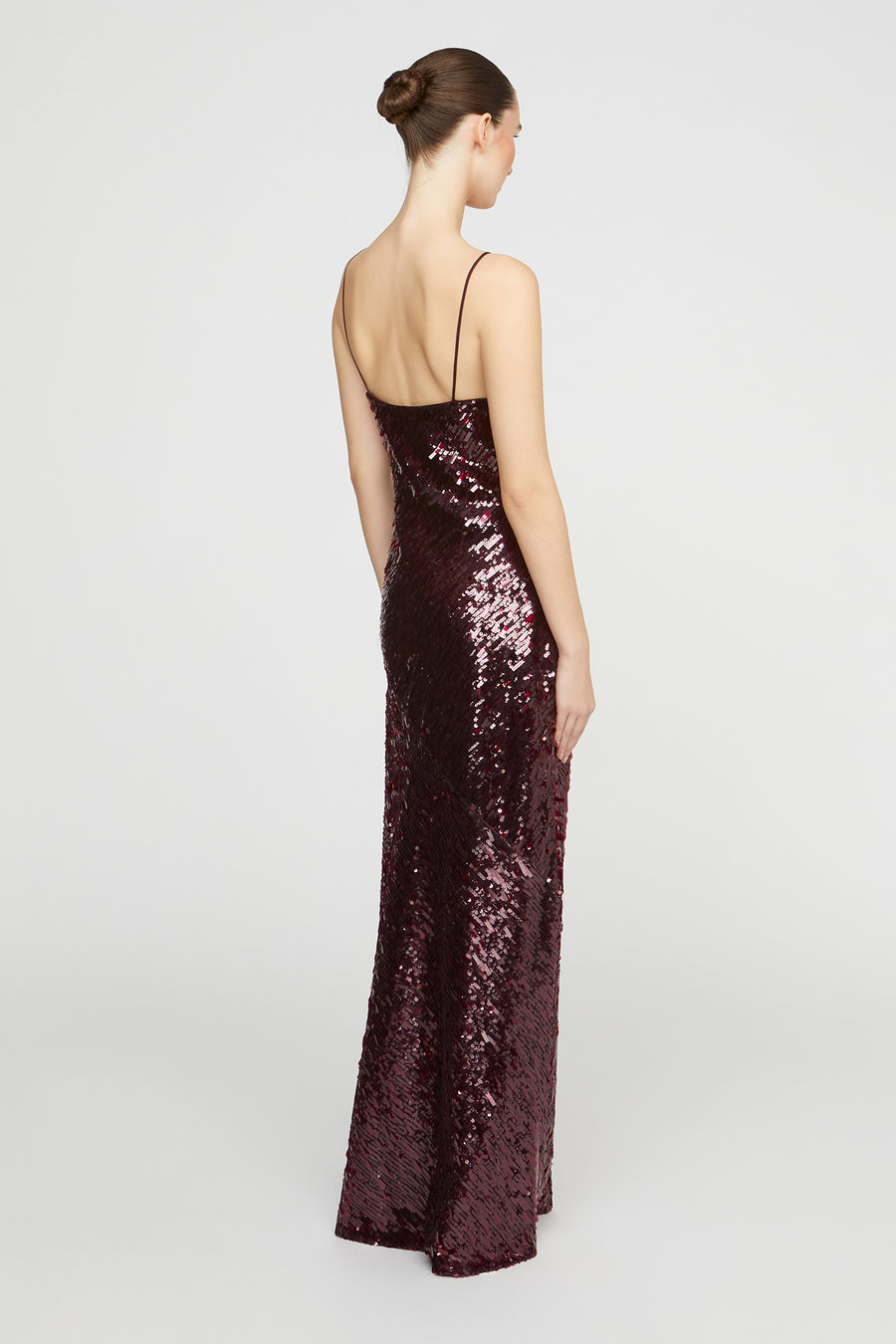 Woman wearing a long, dark sequined dress on a white background