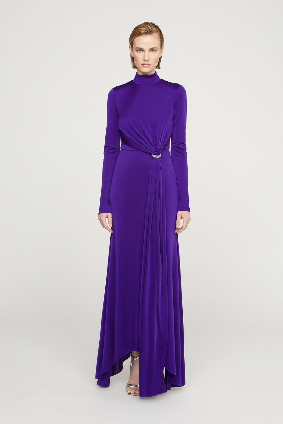 Woman wearing a long purple dress with a high neckline on a white background