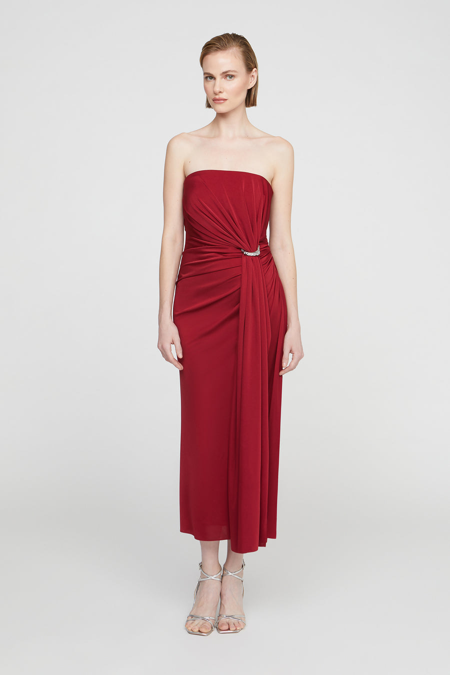 Woman wearing a strapless red dress on a white background