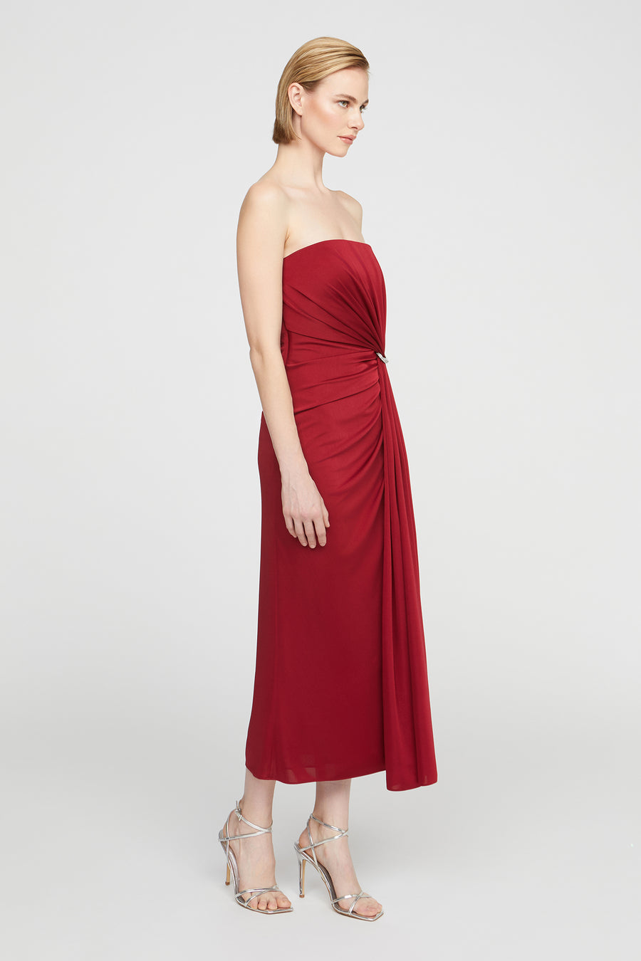 Woman wearing a red strapless dress on a white background