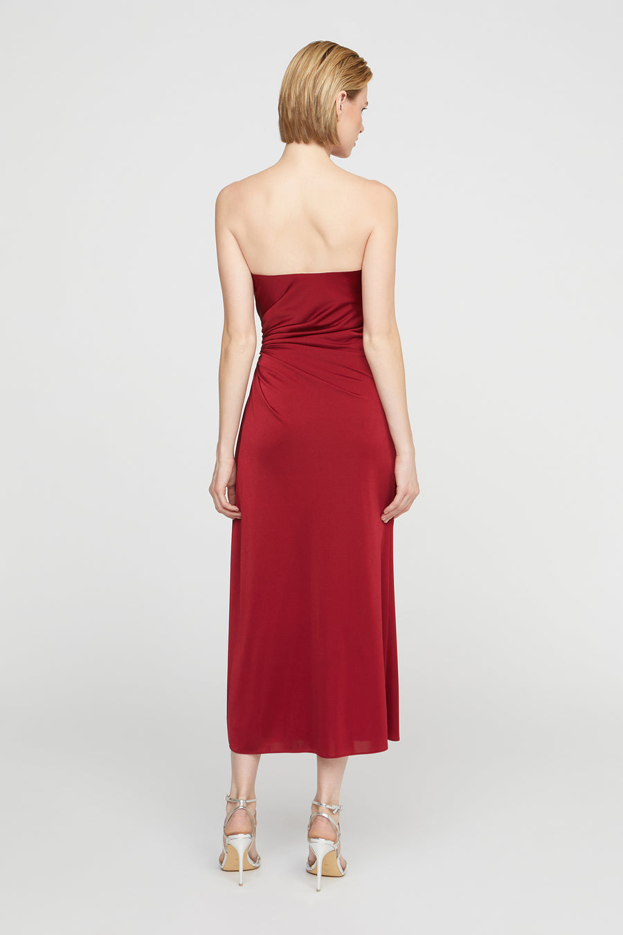 Woman wearing a strapless red dress on a white background