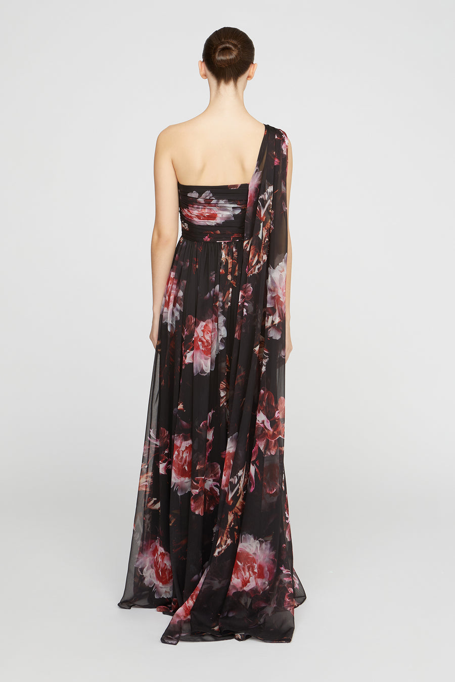 Woman wearing a black floral one-shoulder dress on a white background