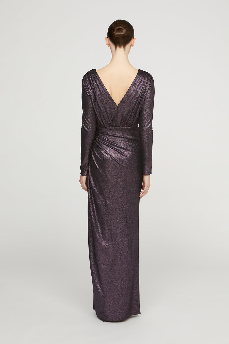 Woman wearing a long, dark purple dress with a V-neckline on a light gray background