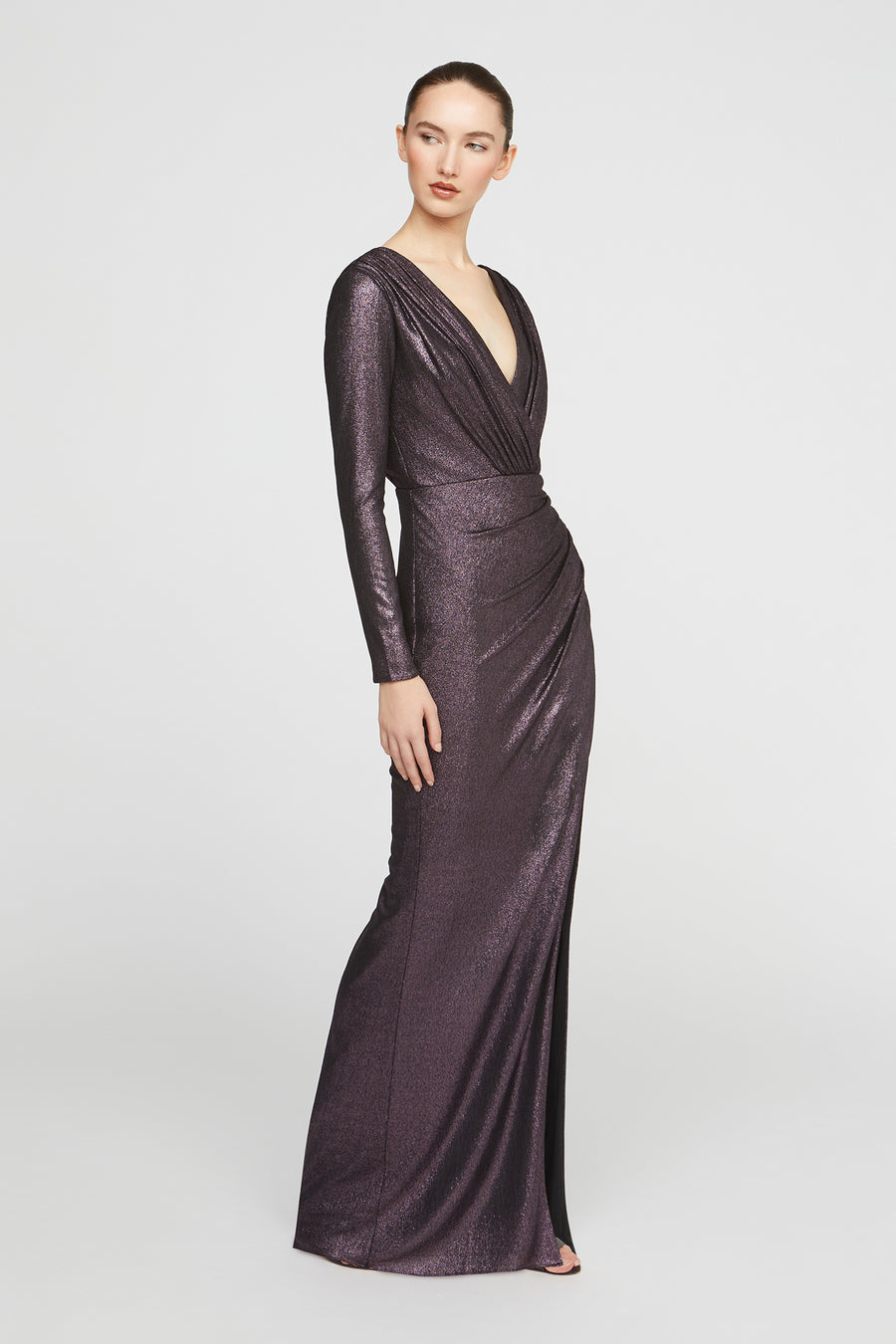 Woman wearing a long, dark purple evening gown on a white background
