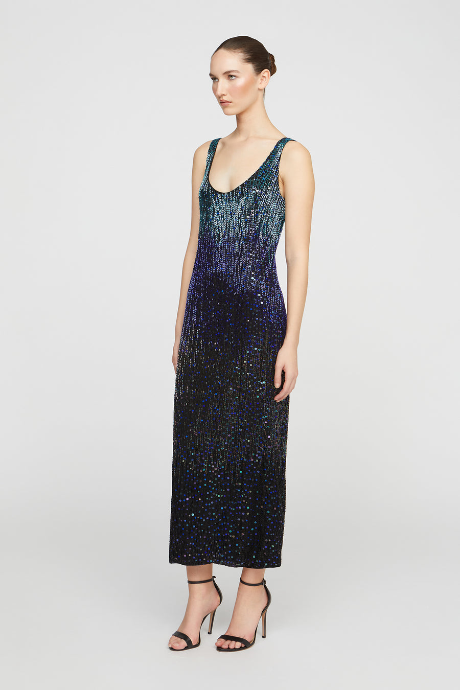 Woman wearing a sleeveless, sequined dress with a gradient of blue and purple on a white background.
