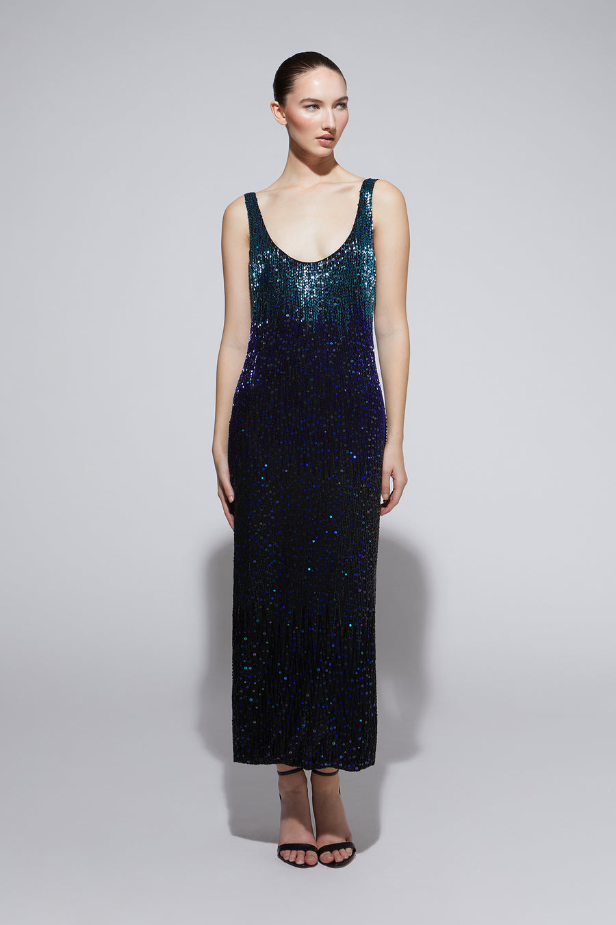 Woman wearing a dark blue sequin dress on a light gray background